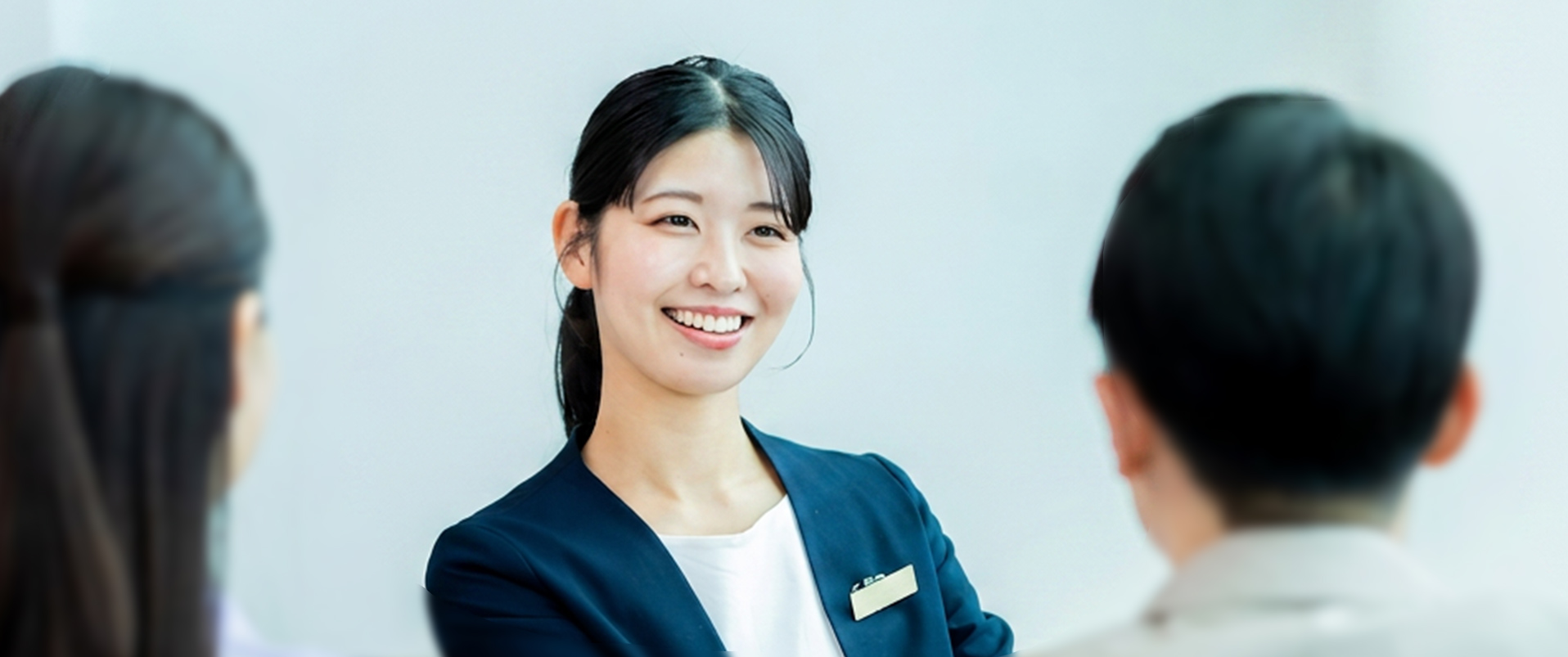 来訪者と向き合い笑顔で応対する女性スタッフ